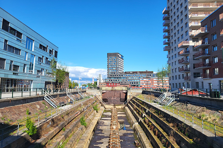 Nedsänkt lång docka med tappsteg längs hela vägen. Omgiven av moderna flerfamiljshus och äldre industribyggnader. 