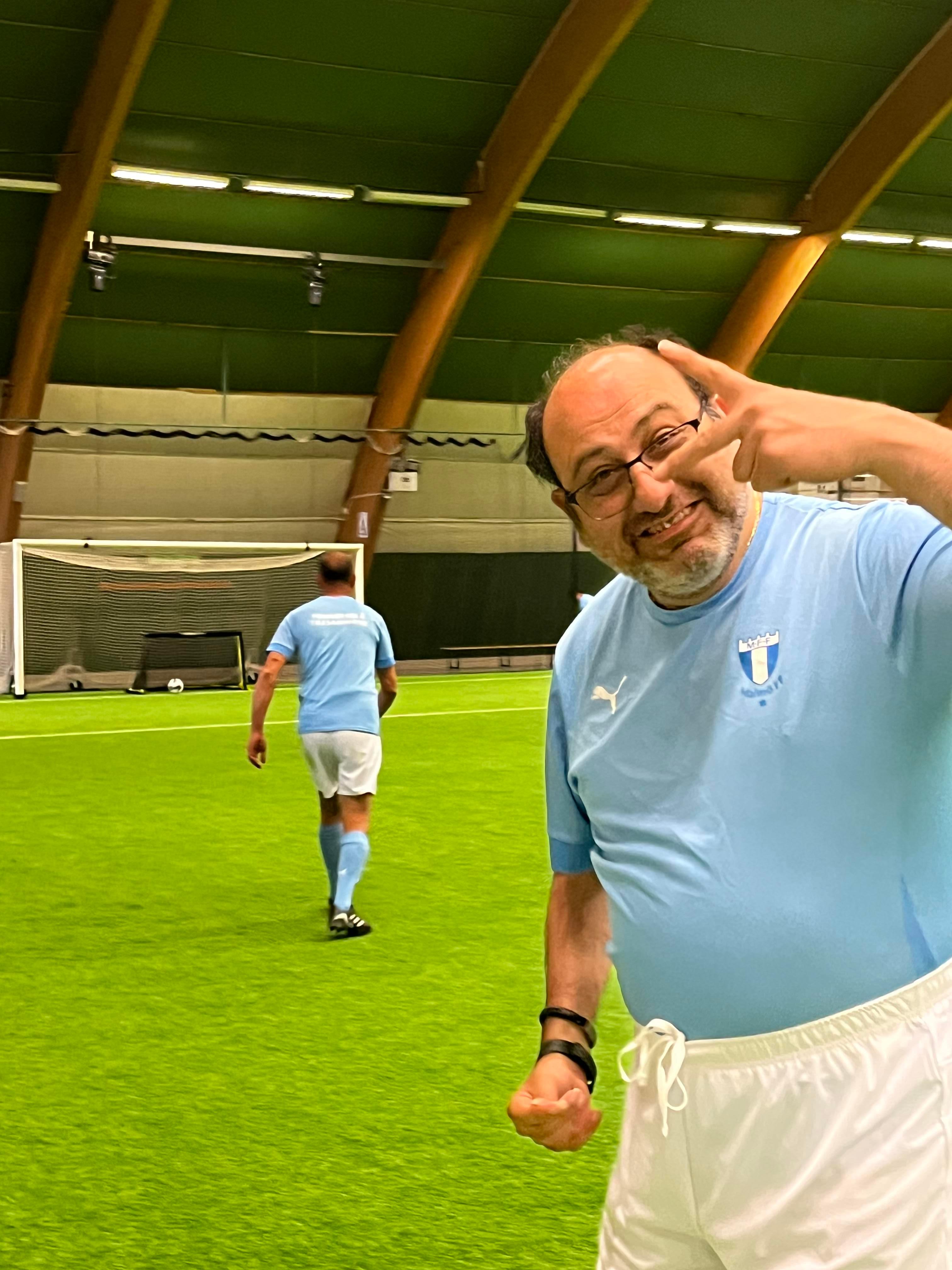 Ali står på fotbollsplanen och ser glad ut mot kameran. Han har på sig MFF-kläder.