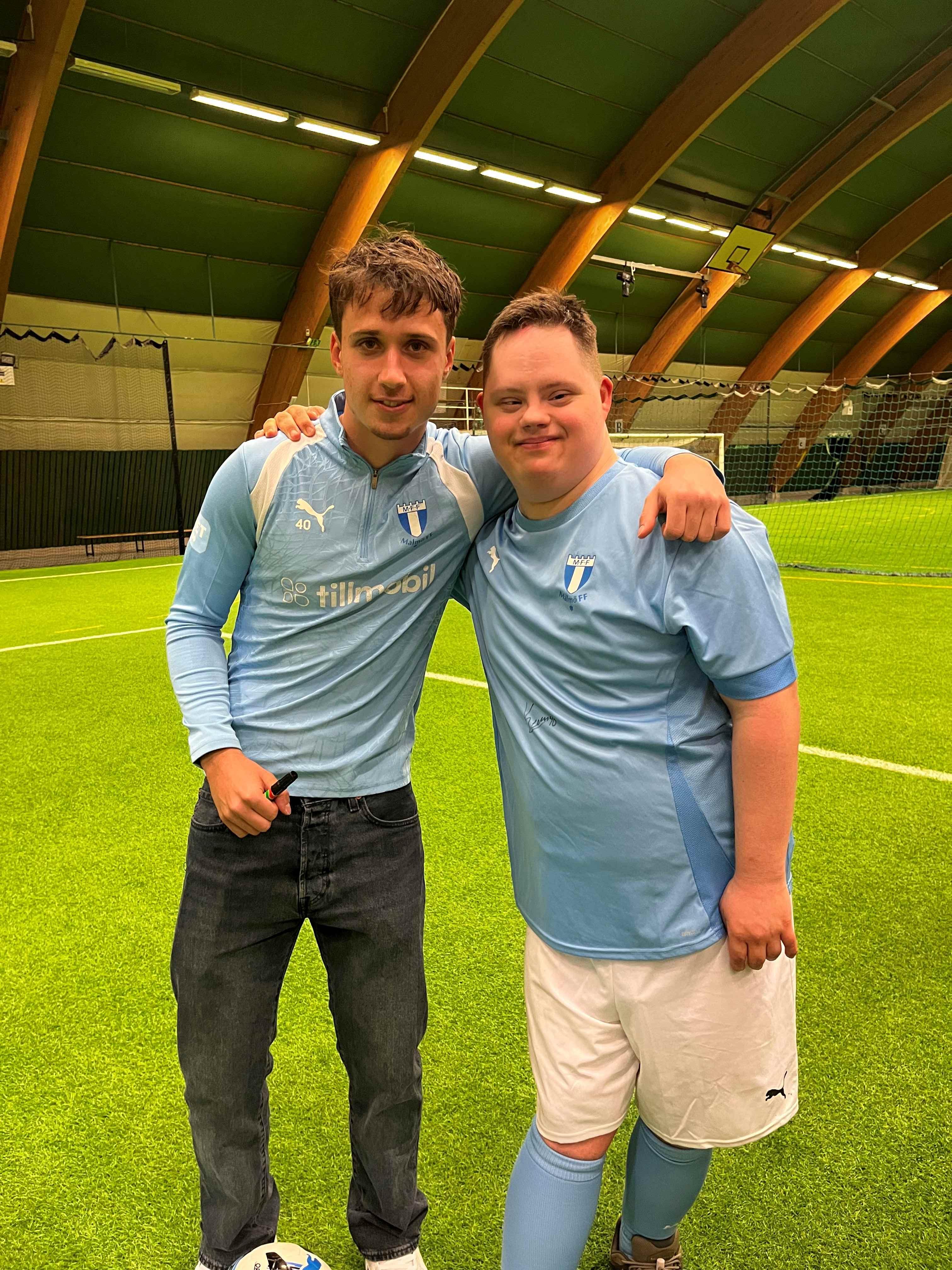 Emiliano håller axlarna om Kenan Busuladzic på fotbollsplanen. De har båda på sig MFF-kläder.