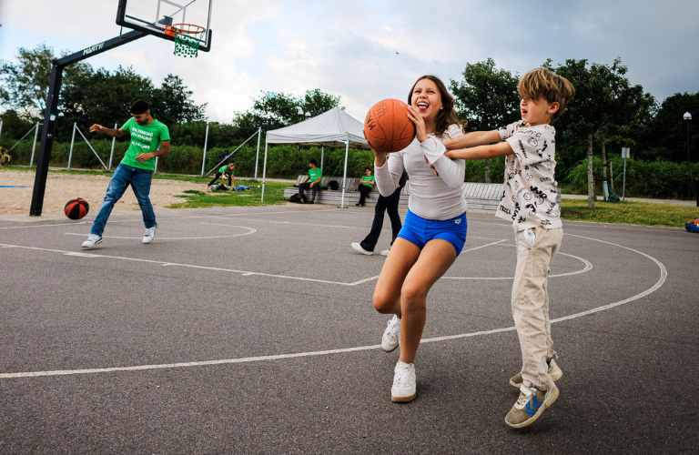 Två unga personer spelar basket på basketplanen på Ribersborgsstranden.