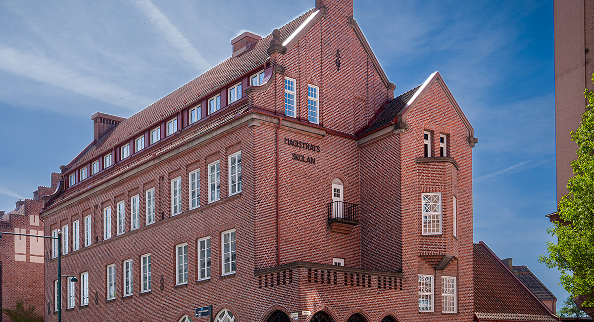 Magistratsgymnasiets röda tegelbyggnad bredvid Triangelns köpcentrum.