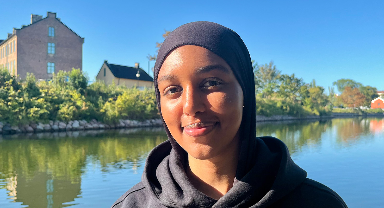Ismahan i huvtröja och sjal vid kanalen i närheten av skolan.