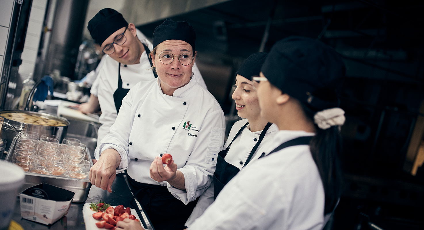 Lärare i köket hjälper till att visa hur en dessert med jordgubbar tillagas.