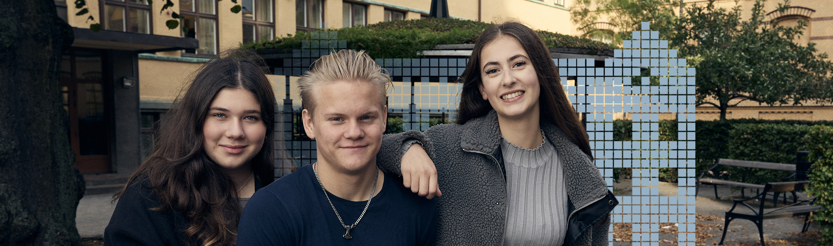Tre glada elever på skolgården.