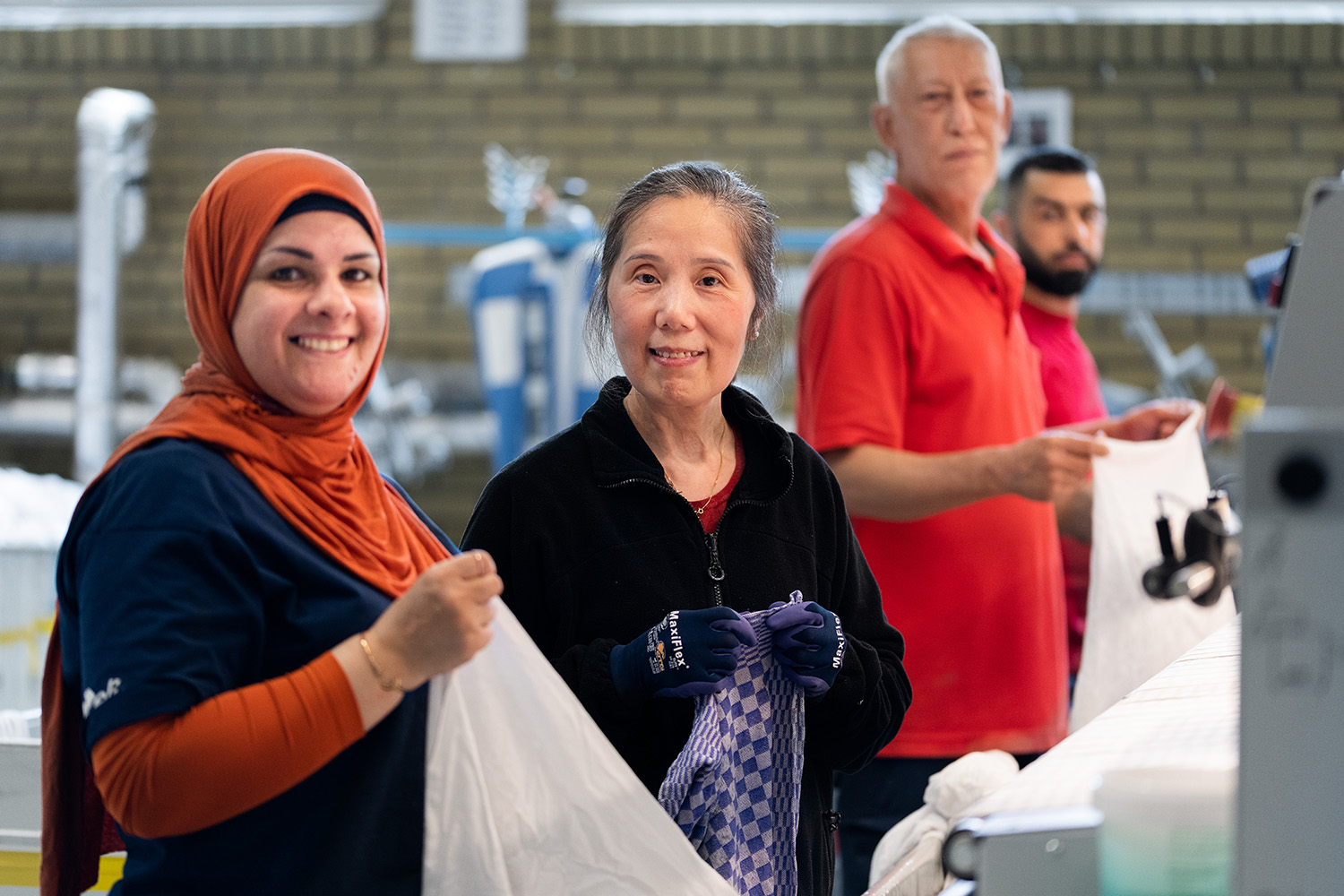 Fyra medarbetare står och manglar textilier