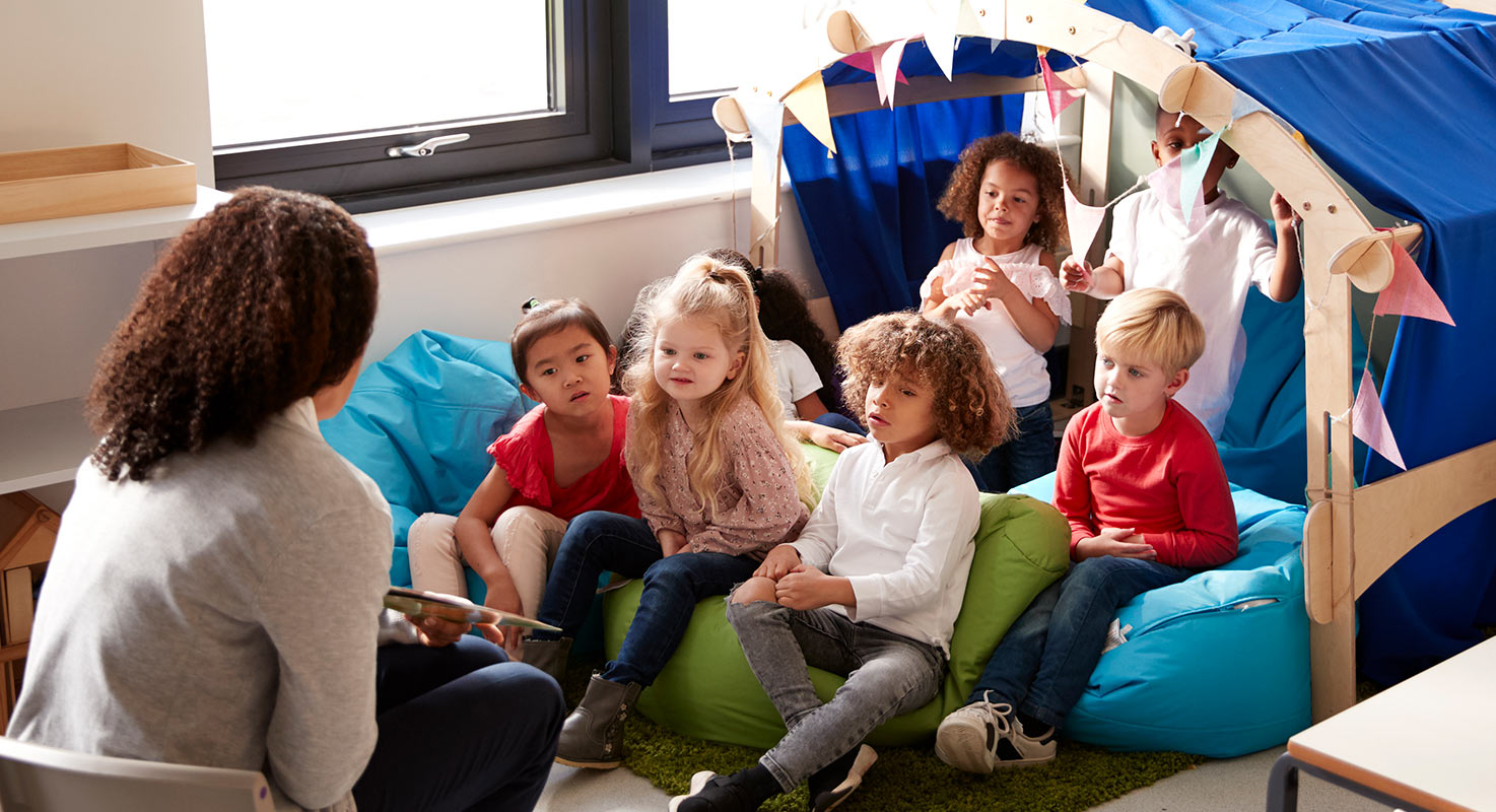 Barn på en förskola lyssnar intresserat när en
pedagog läser i en bok.