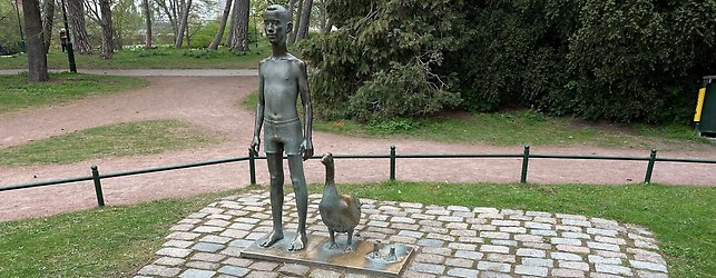 Bronsskulptur som avbildar en pojke och en gås, i en park.