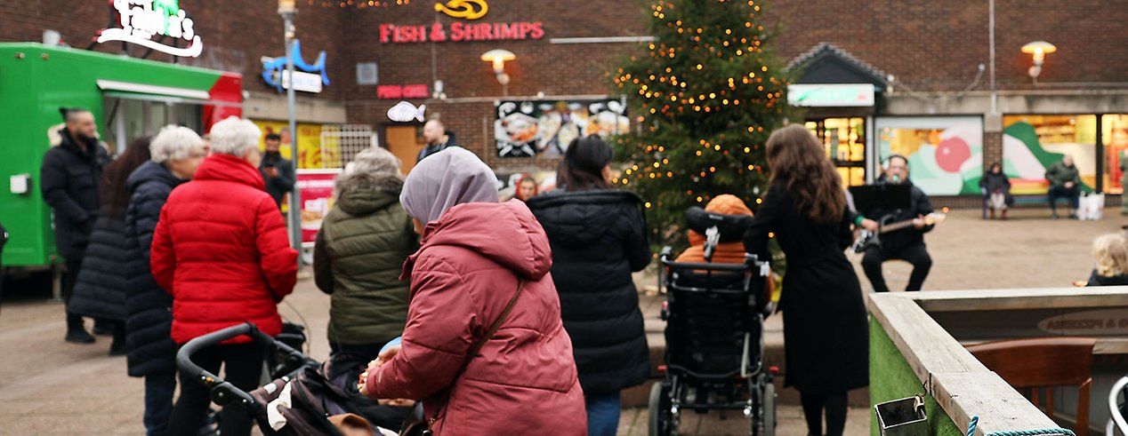 Ett torg med julgran trubadur och folksamling.
