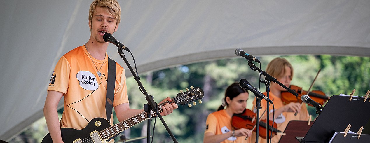 Musiker på scen. En gitarrist som sjunger i förgrunden. 