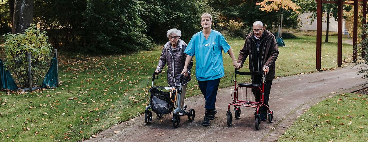 Undersköterska Anna Grimström tar en promenad med Grete Nilsson och Sixten Ulfskans i den parkliknande miljön vid vård- och omsorgsboendet Danska vägen.