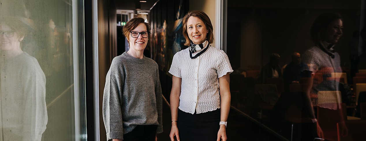 Jeanette och Marie-Louise står i en korridor och ler mot kameran.