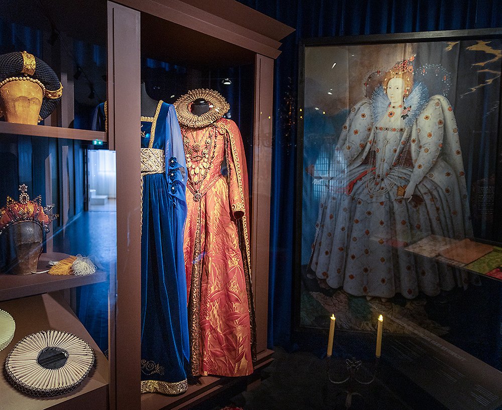 Fotografi i monter, i montern syns två klänningar som tillhört drottningar, samt en målning av drottning Elisabet II