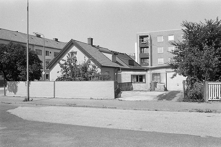 Del av gata med villa och höghus i bakgrunden.