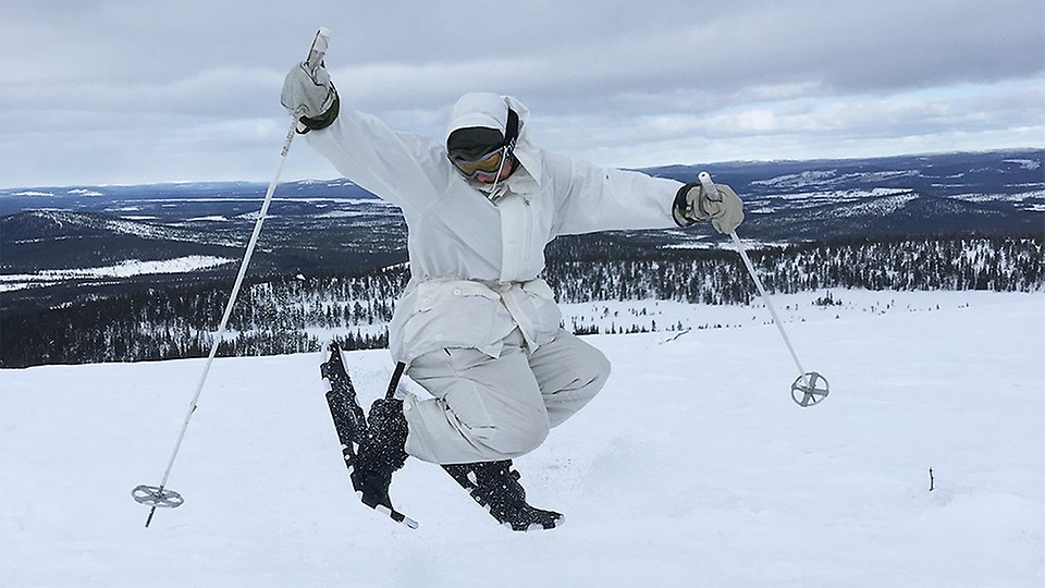 En elev i vinterlandskap gör ett högt skutt stående på skidor.