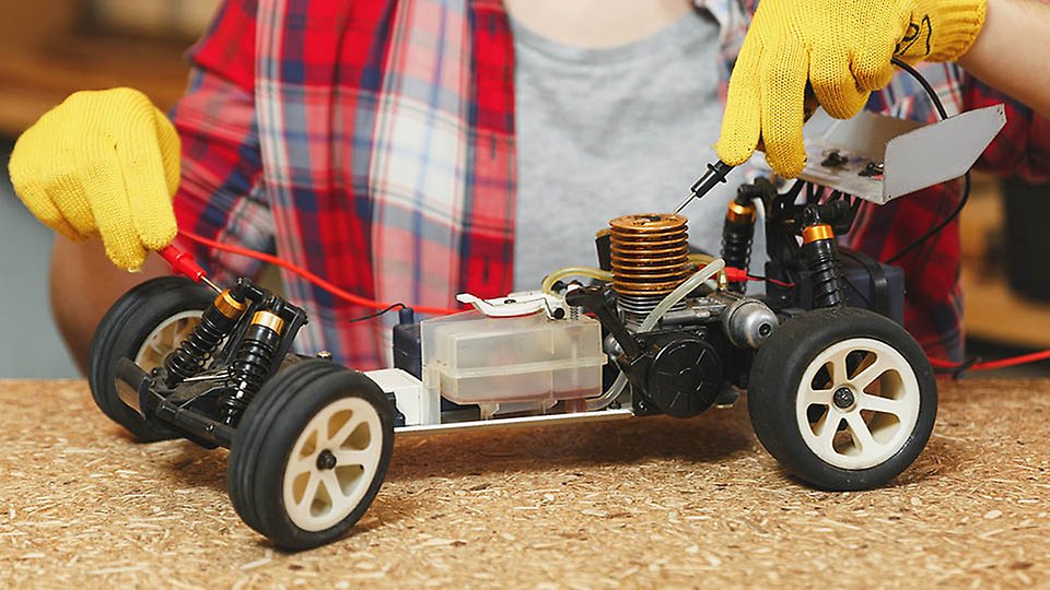 Närbild på modellbil. En elev jobbar med att få modellbilen att styras smart i kursen mekatronik.