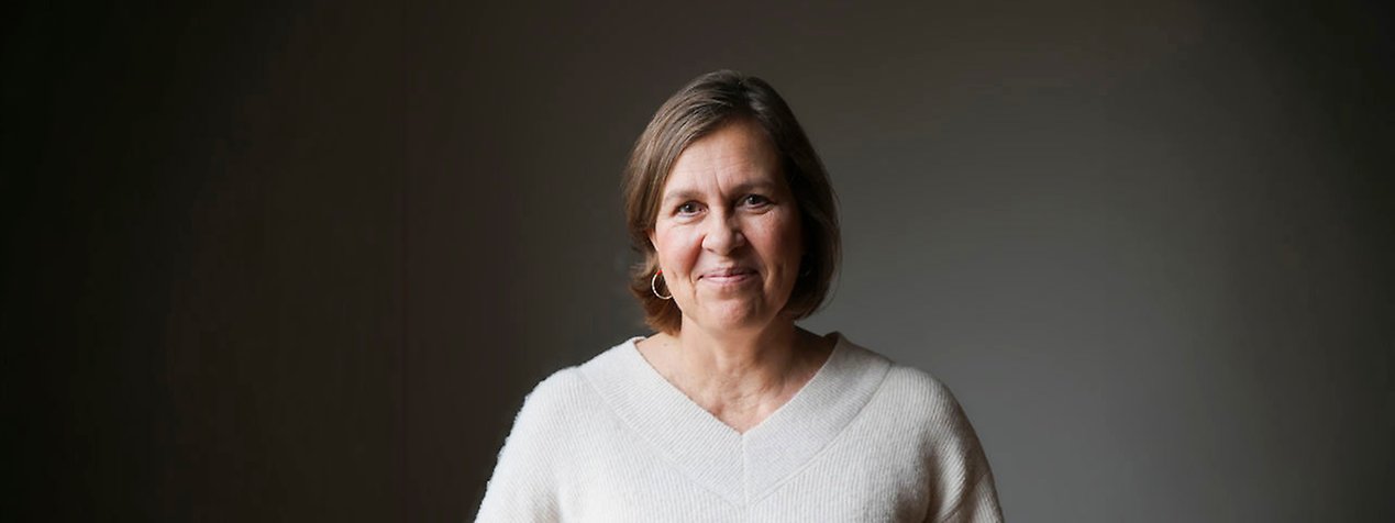 Annika har en brun page och är klädd i en vit tröja.
