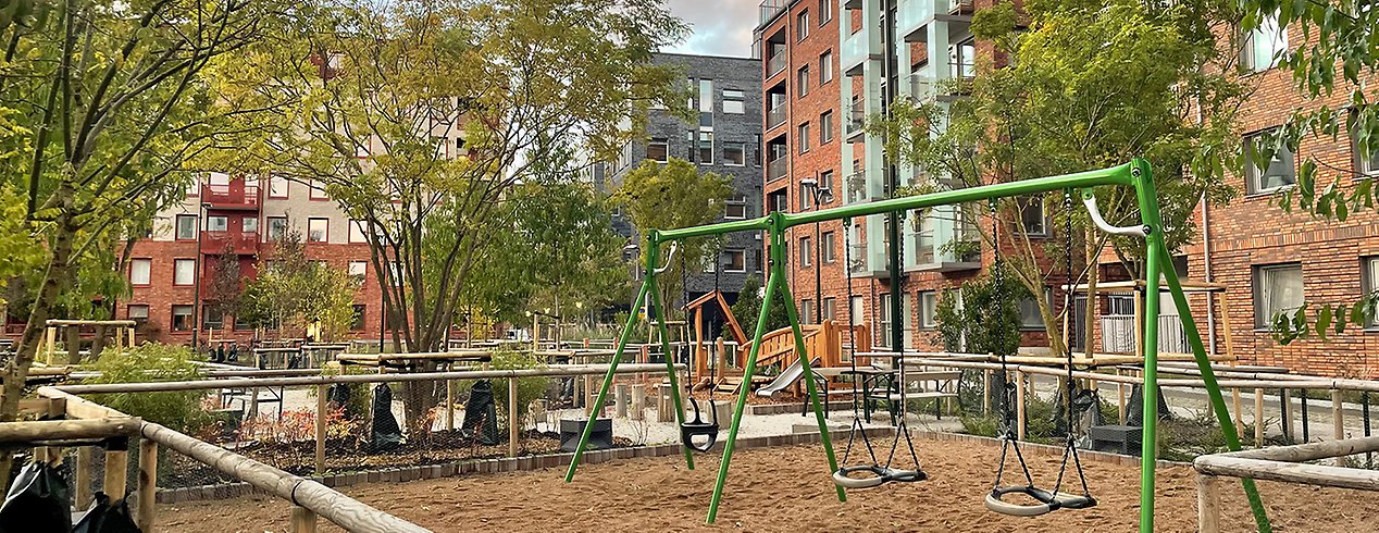 En grön gungställning med träd och buskar runtomkring