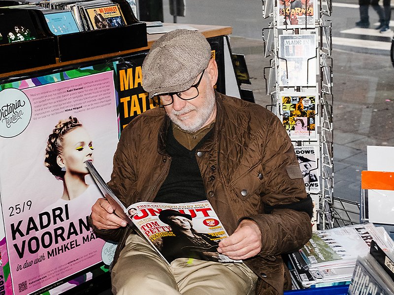 En person bärandes keps och jacka sitter och läser en tidning i en skivbutik på Spångatan.