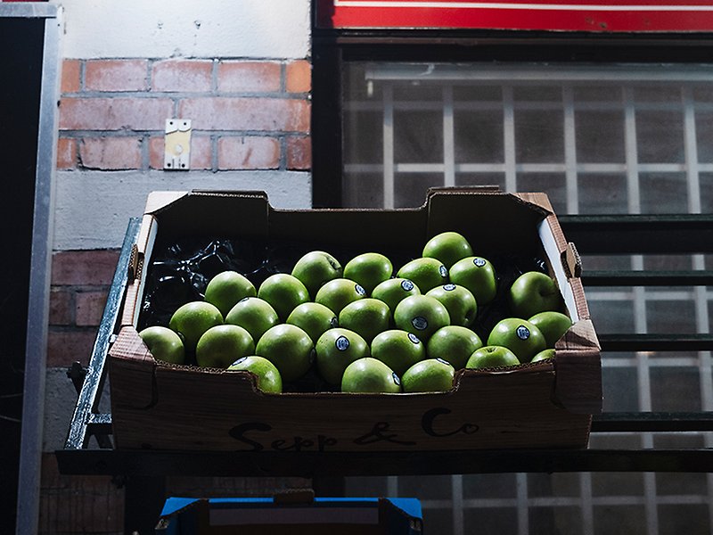 Gröna äpplen i kartong utanför en butik på Möllan.