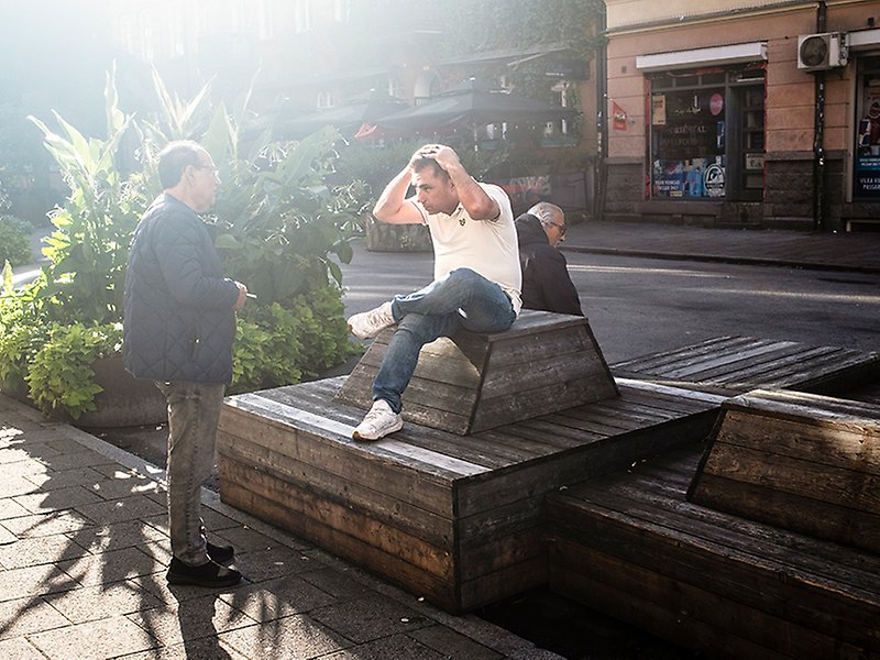 Tre personer hänger vid sittbänkarna på Claesgatans sommargata.