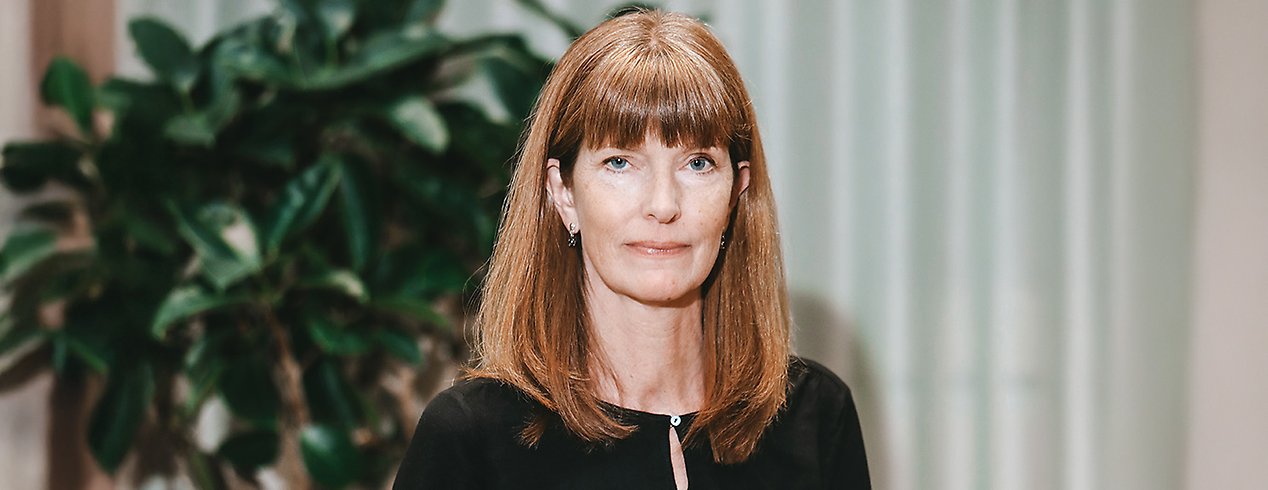 Lena har långt rödbrunt hår med lugg och en svart tröja.