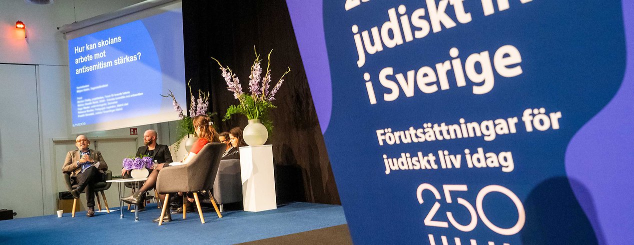 En scen med personer som har panelsamtal. Det står 