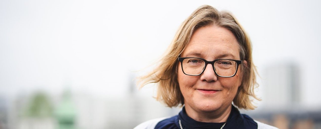 En leende Anna Wittgren på en takterrass, iklädd mörkblå blus och ljusgrå kofta.