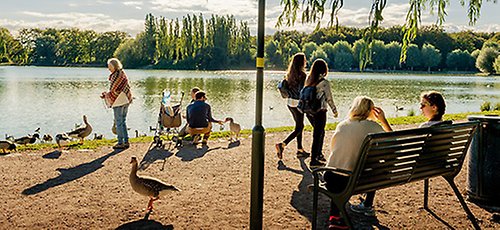 Utsikt över stora Pildammen. Folk njuter av solen.