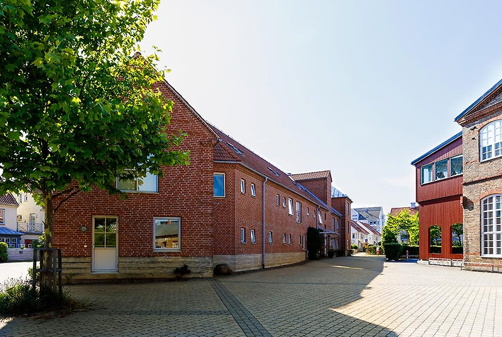 Det avlånga tegelhuset ligger på en öppen och lugn stenlagd gata i ett mysigt område med låga hus.