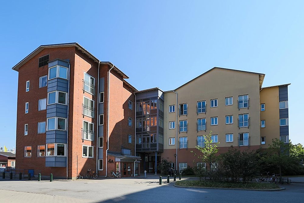 Där det röda tegelhuset och den gula byggnaden möts finns våra balkonger med utsikt över entrén.