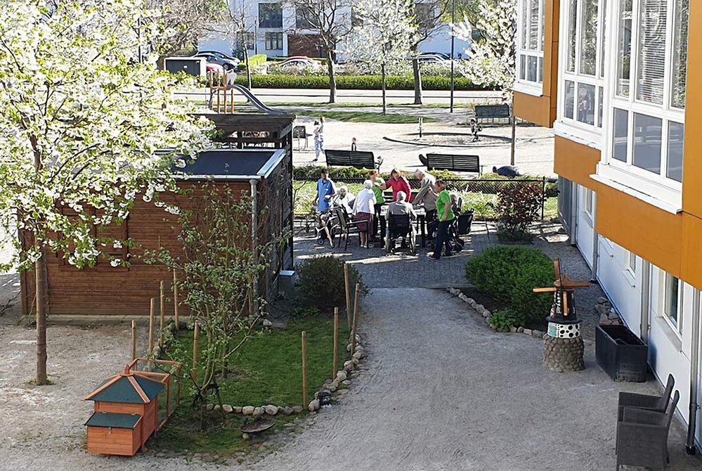 Vid uteplatsen kan man umgås i skuggan av huset med utsikt över en livfull lekplats.