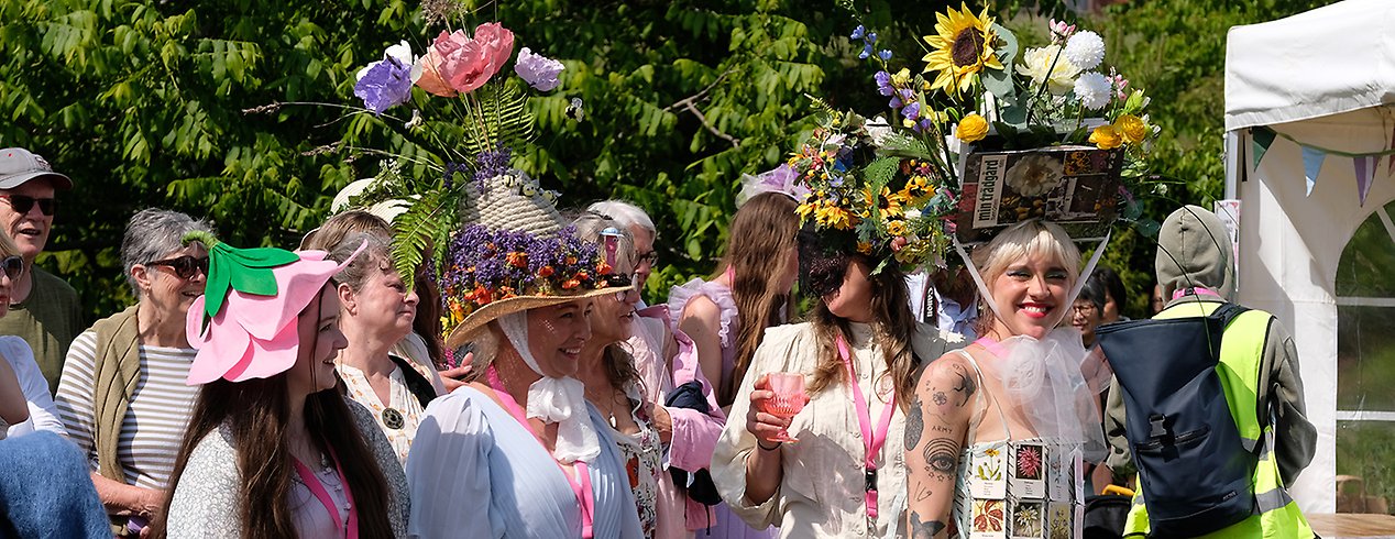 Några kvinnor i fantasifulla blomstrande kreationer på huvudet. 