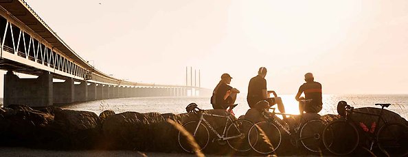 Personer sitter i solnedgång och tittar på Öresundsbron