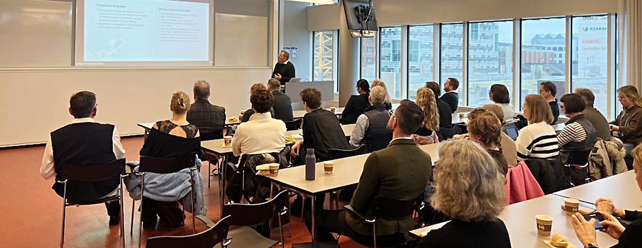 Personer lyssnar på föreläsare som visar bild.