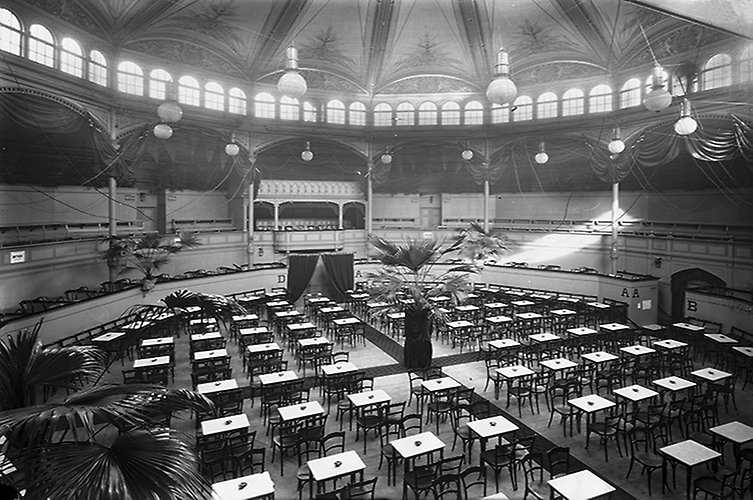 Bord med stolar runtom på hela arenan, läktaren runtom. 