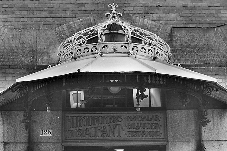 Dekorativ baldakin ovanför ingången, utsmyckad med sirliga mönster och ett skärmtak. 