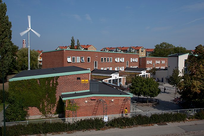 Låga byggnader i rött tegel med platta svarta tak och ärgade gavlar.