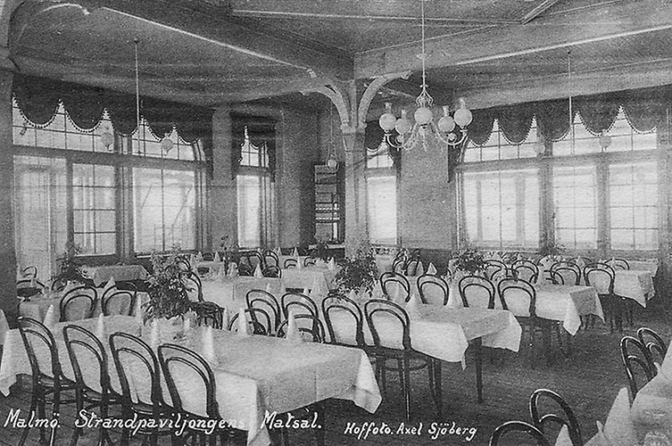 Bord på rad med vita dukar och svarta stolar runt om.