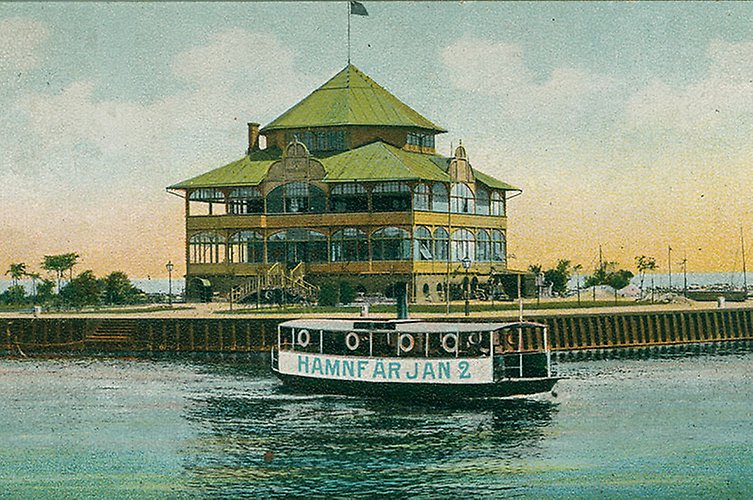 Vykort i färg med Strandpaviljongen och en båt i vattnet framgör byggnaden.