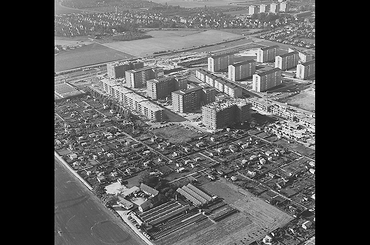 Svartvitt flygfoto med låga och höga hus.