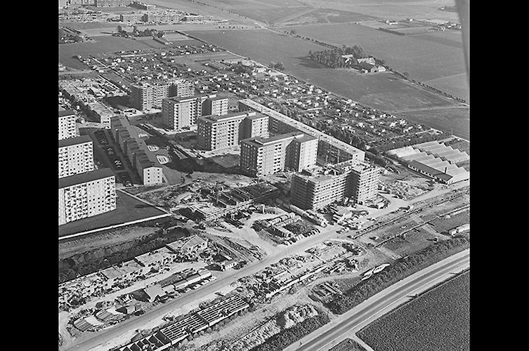 Svartvitt flygfoto med låga och höga hus. 