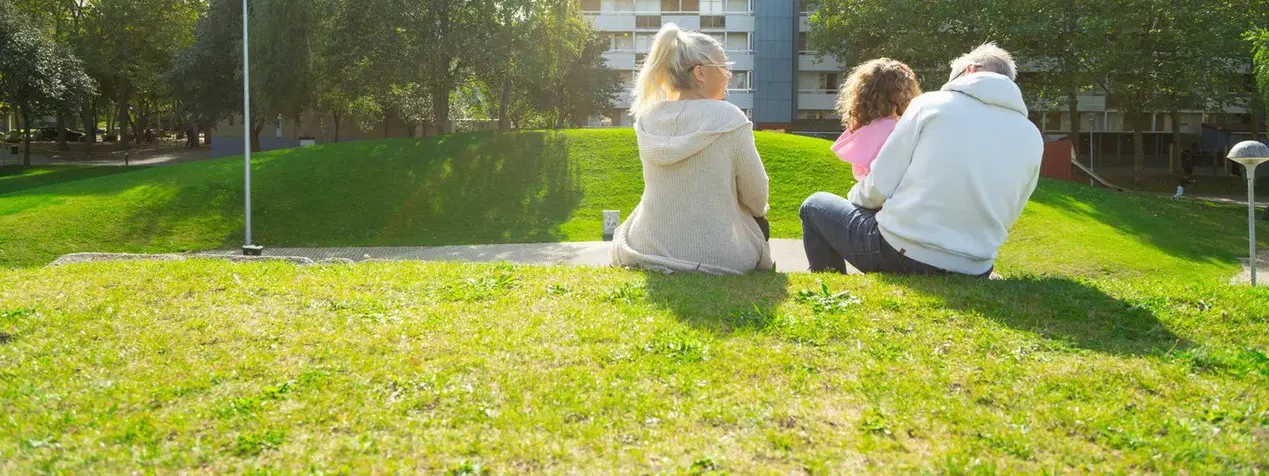 Kvinna, barn och man sitter på en kulle.