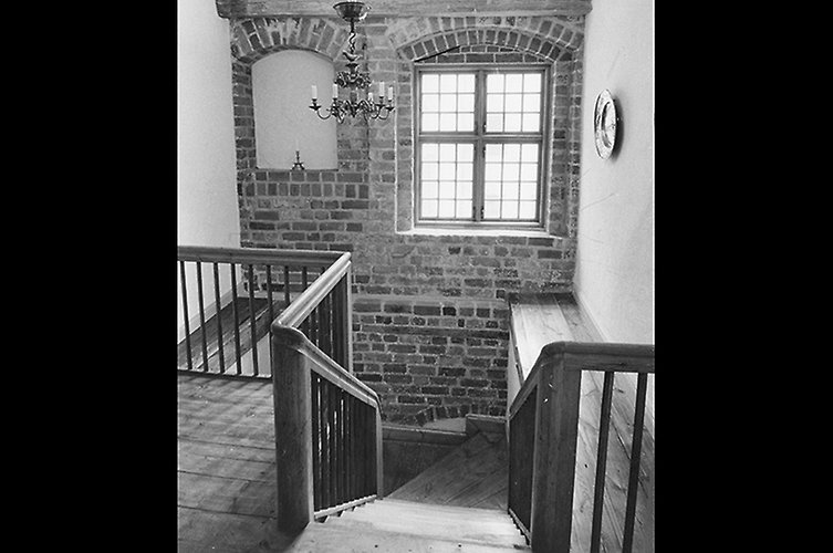 Äldre svartvitt foto på trapphus i äldre byggnad. Fint ljusinsläpp från fönster. 