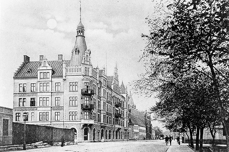 Äldre svartvitt foto på pampig byggnad i flera våningar med ett slottstorn.