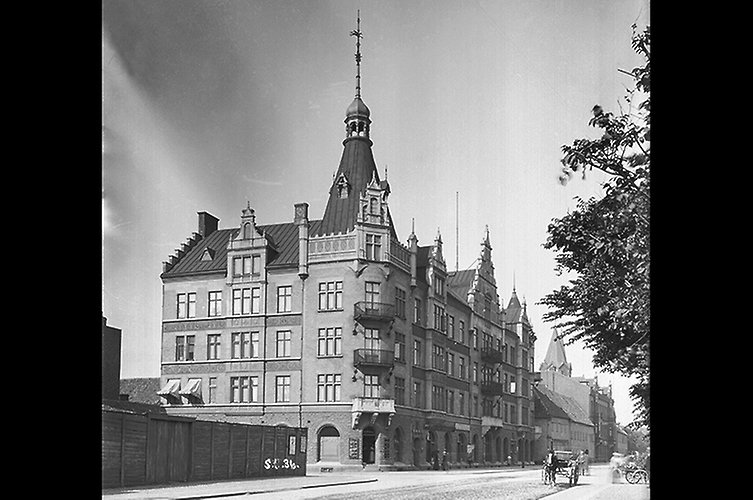 Äldre svartvitt foto på pampig byggnad i flera våningar med ett slottstorn.