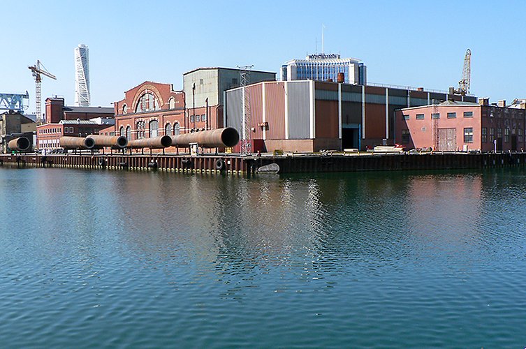Äldre industri och hamnmiljö med hamnbassäng i förgrunden. 