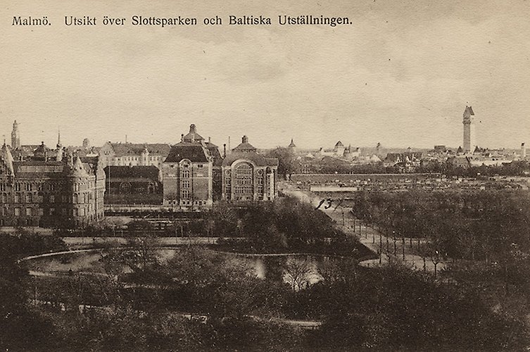 Äldre svartvitt foto över parkområde med stadsbebyggelse i bakgrunden.