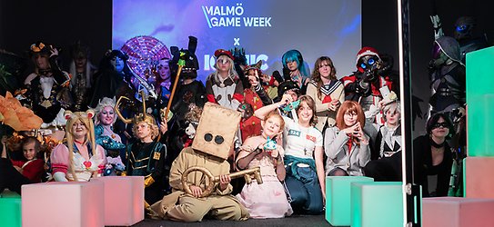 Flera personer utklädda i cosplay-kostymer står på en scen. I bakgrunden står det Malmö Game Week.