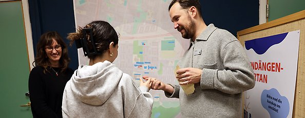 Besökare får en klisterlapp av en leende man och kvinna för att sätta på en karta.