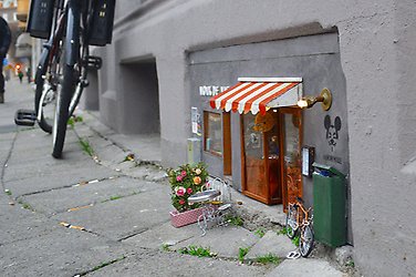 Miniatyrhus insprängt längst ner i fasaden på bostadshus på gata i Malmö. 